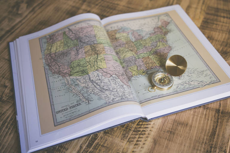 Picture of a United States map inside a book with a compass on top.