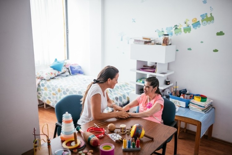 Developmental Disability Nurse supporting a child patient with daily living activities in a home setting, showing essential skills for independence support.