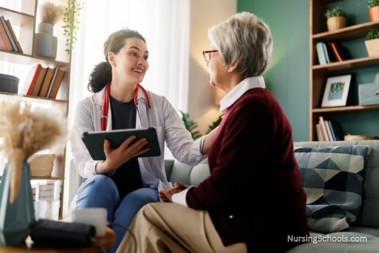 Geriatric Nurse talks with an elderly woman on a couch during a home healthcare visit, highlighting assessment skills and communication skills used to monitor health changes, mobility, and daily functioning.