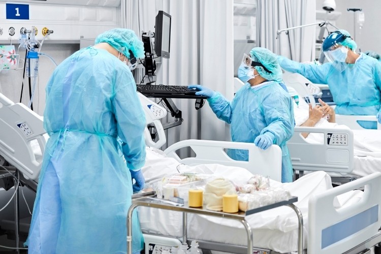 ICU Nurse administering medications and treatments to a critically ill patient in a hospital bed.