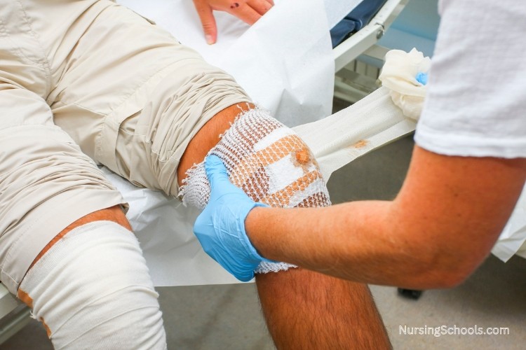 Wound Care Nurse assesses, treats, and monitors the healing of a wound on a patient's knee caused by injury.